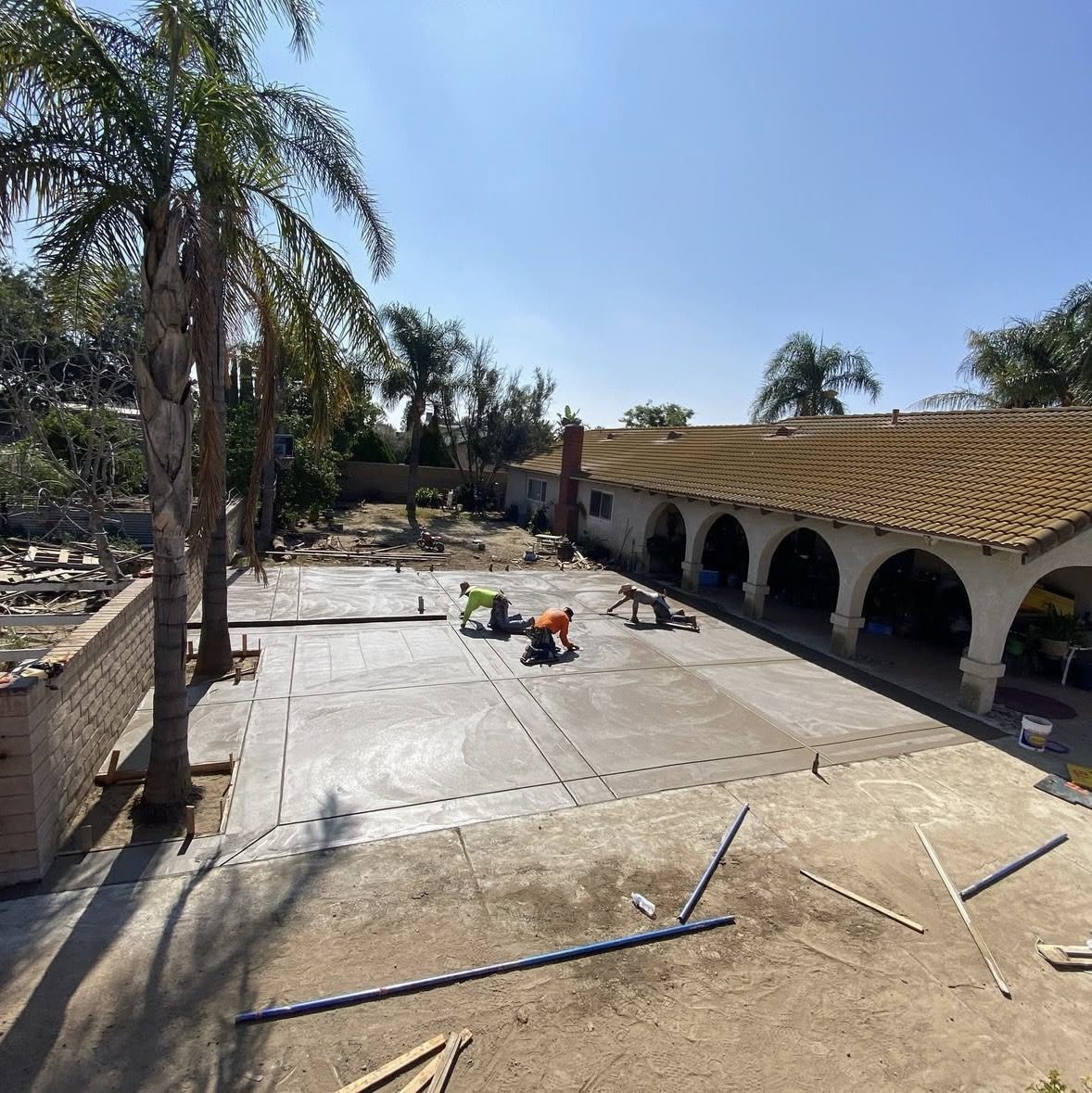 Crew hand-finishing a large backyard patio pour