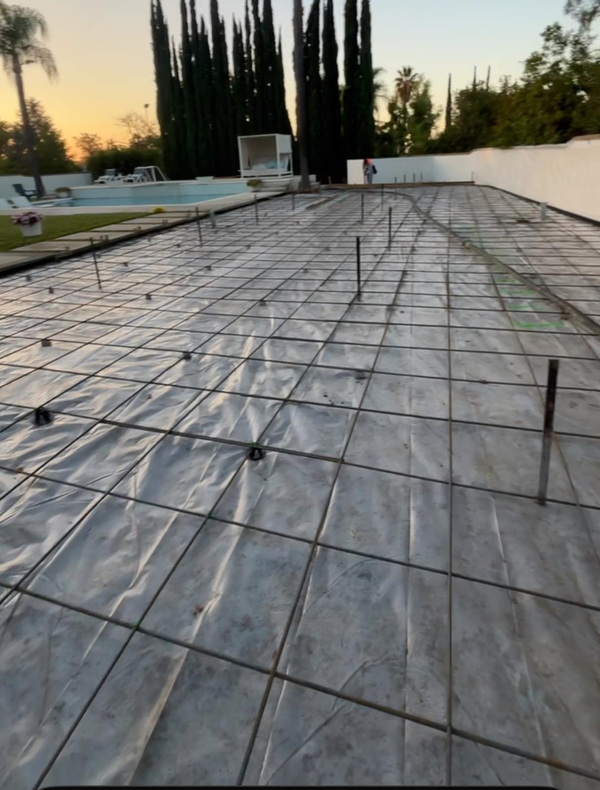 Pool deck prepped with vapor barrier and rebar grid before pouring