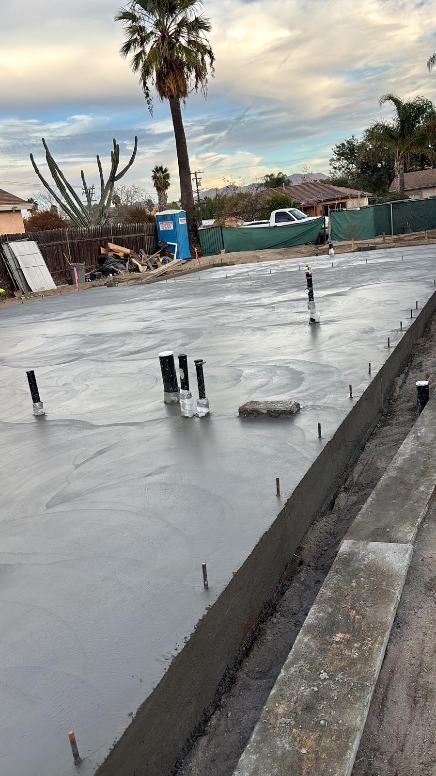 Freshly poured concrete slab foundation with plumbing stub-ups